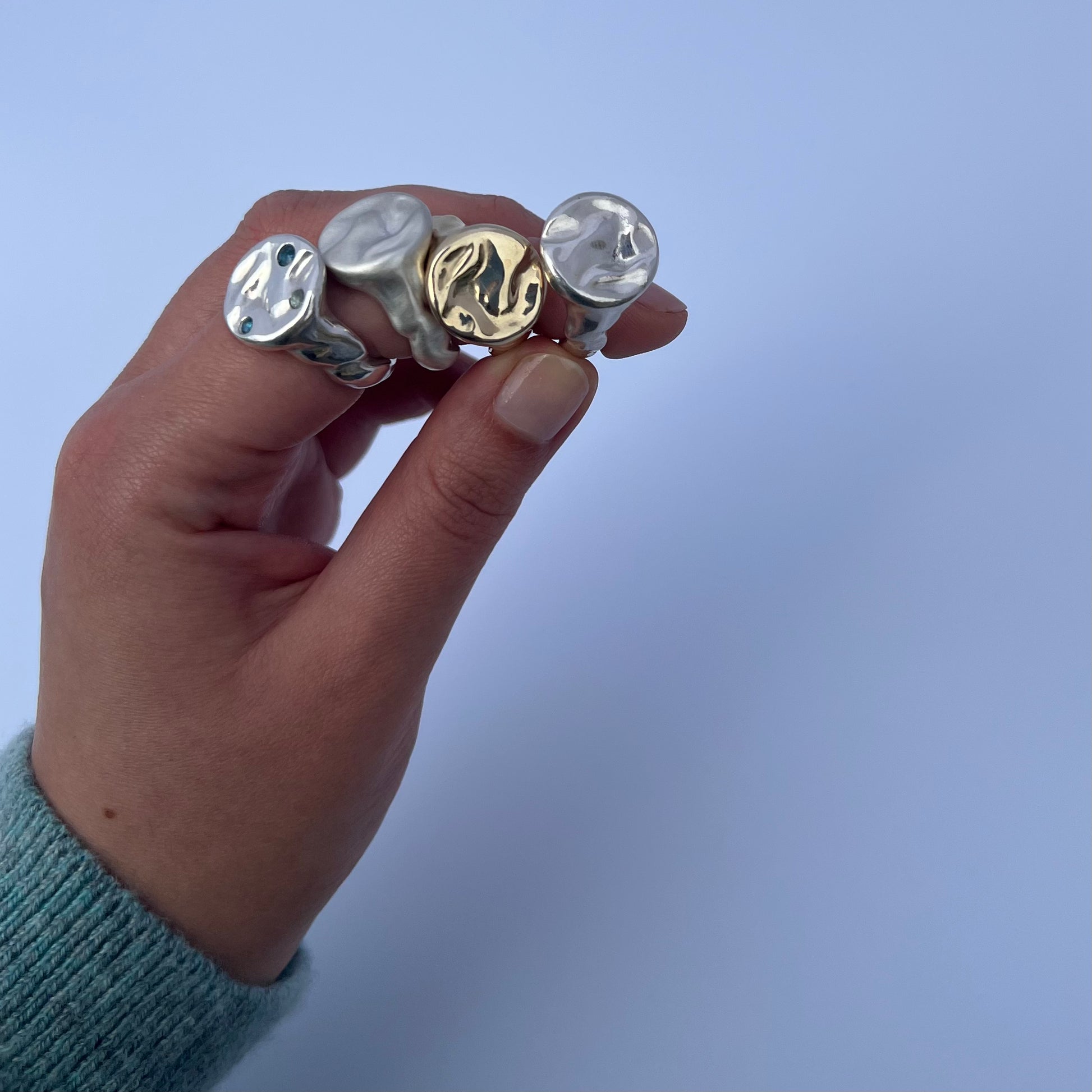 Four splash rings held by a hand on a white background