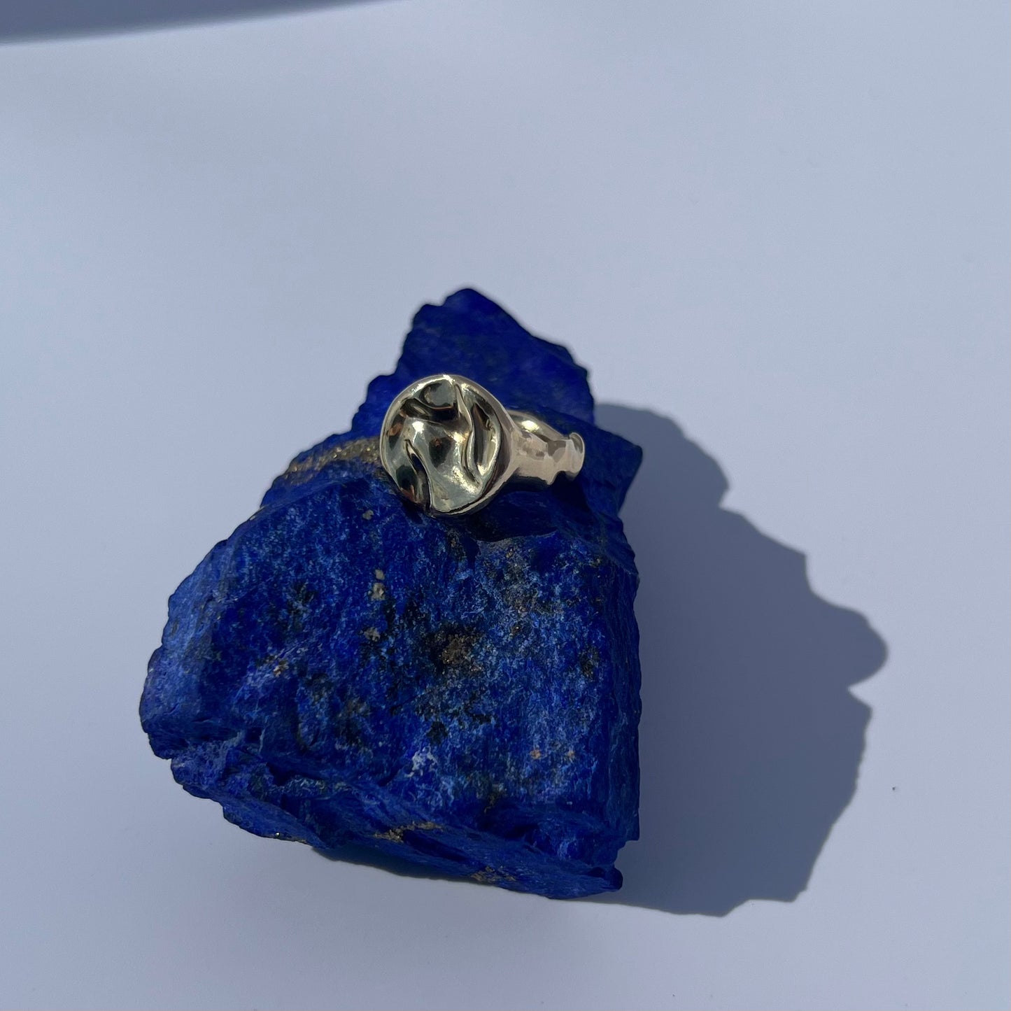 The 9ct yellow gold Splash ring sitting on a block of lapis lazuli on a white background.
