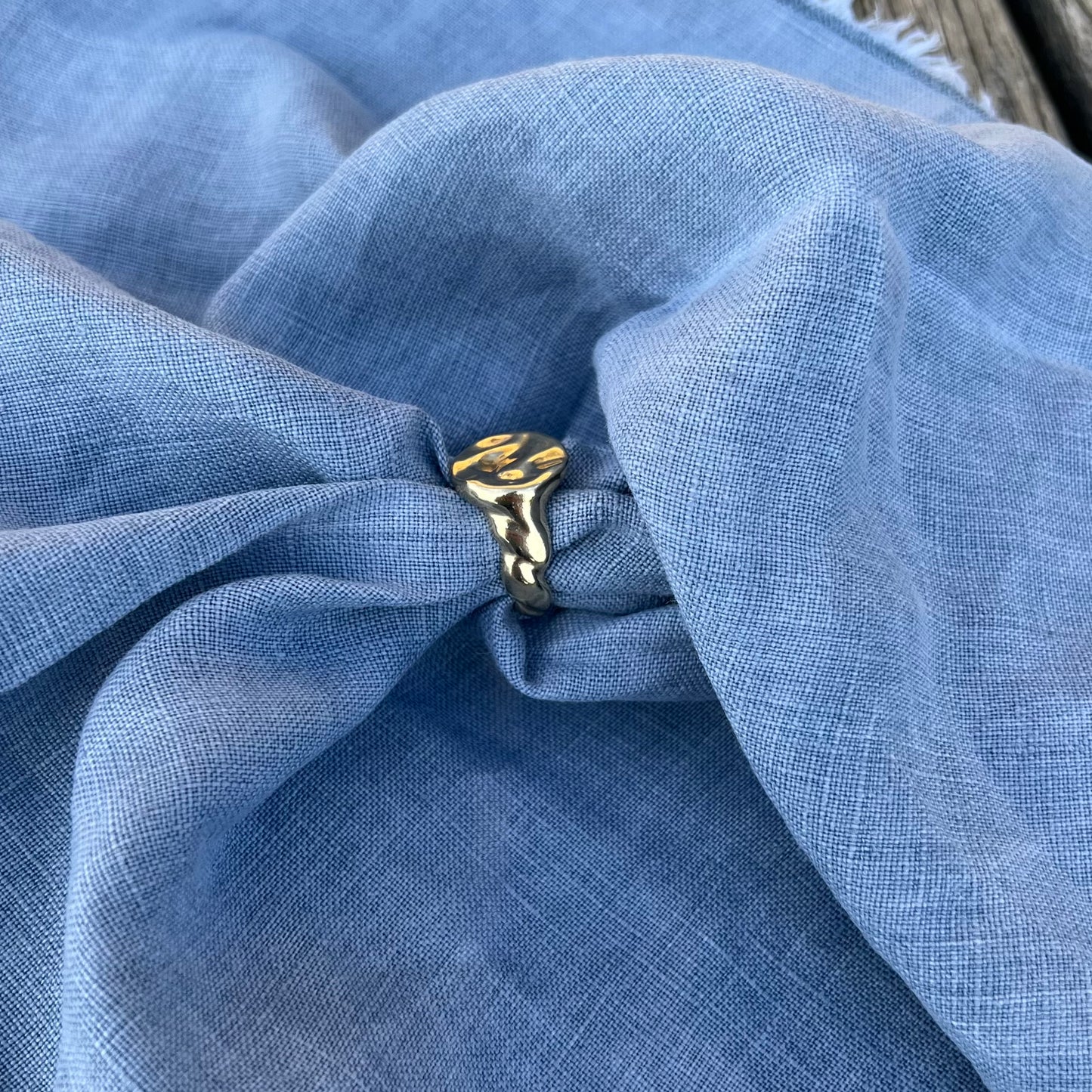 A 9ct yellow gold splash ring on a background of blue linen.