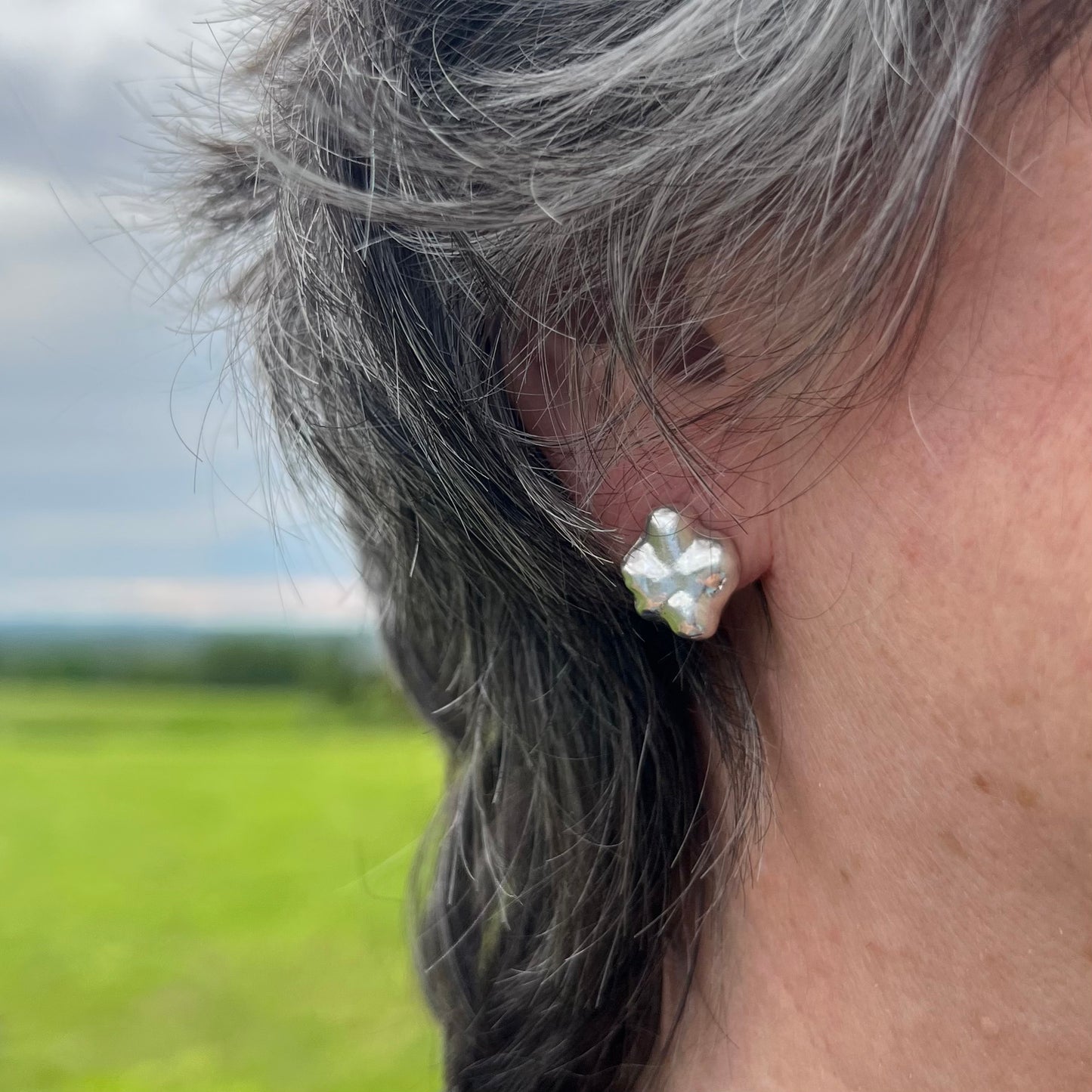 The swirling stud earrings on a woman with short black hair.
