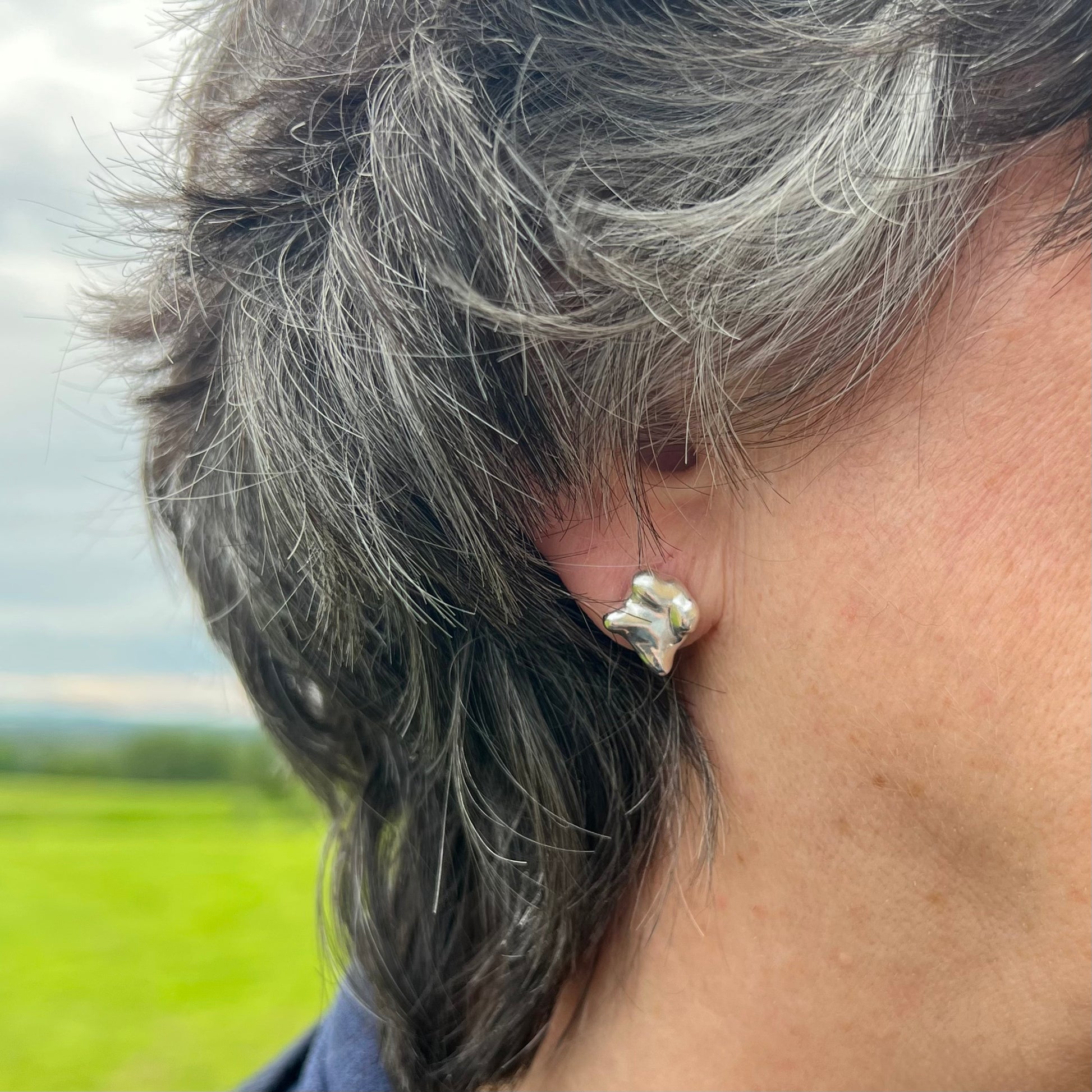 The swirling stud earrings on a woman with short black hair.