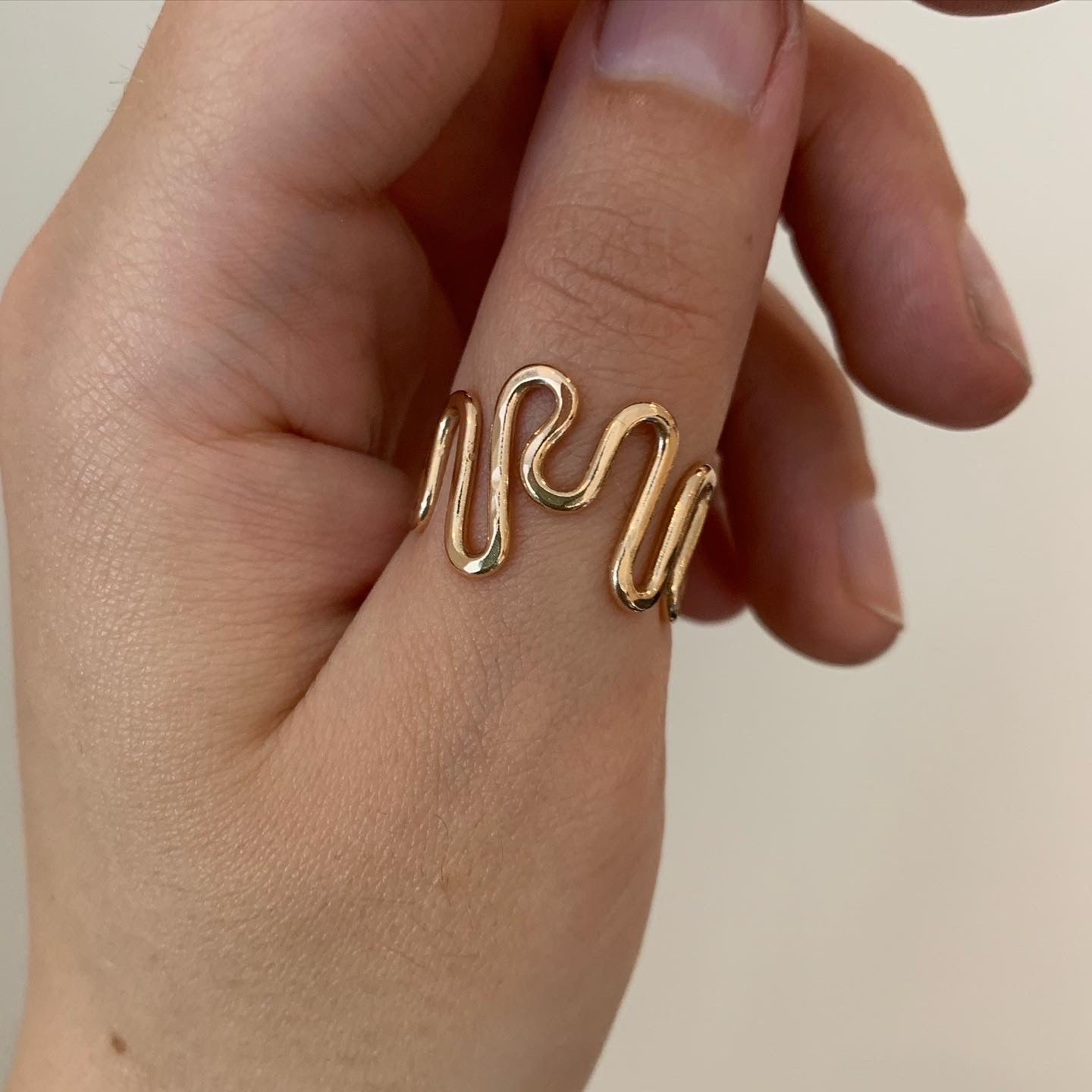 A gold-filled ripple ring pictured on a hand.