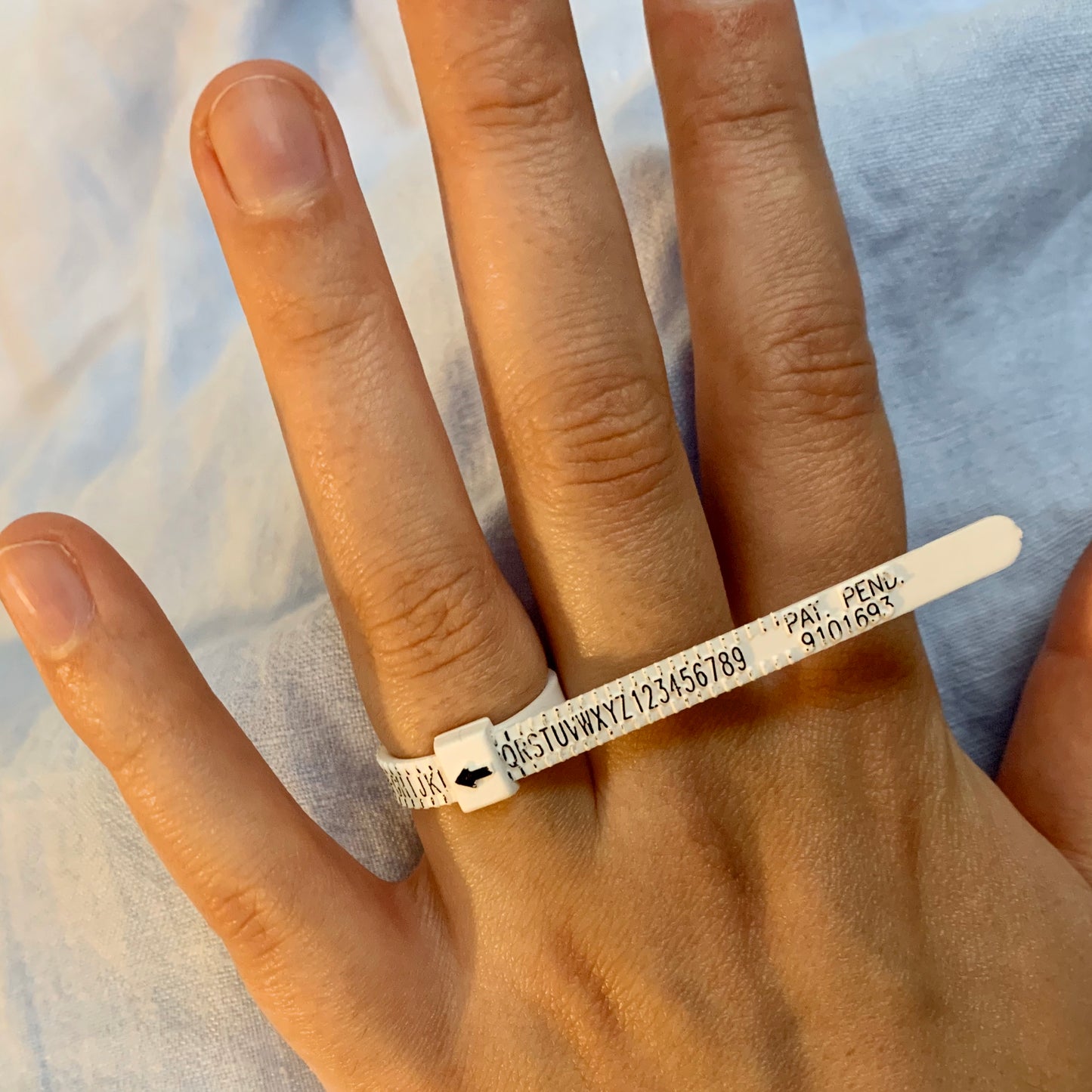 An adjustable ring sizer pictured on a finger.
