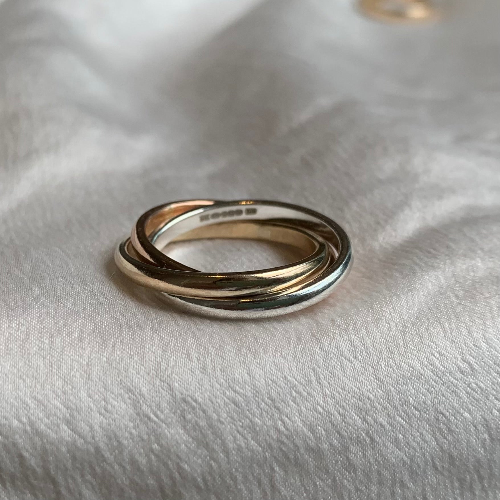 A triple-interlocking Russian wedding ring featuring a sterling silver band, a 9ct yellow gold band and a 9ct rose gold band.