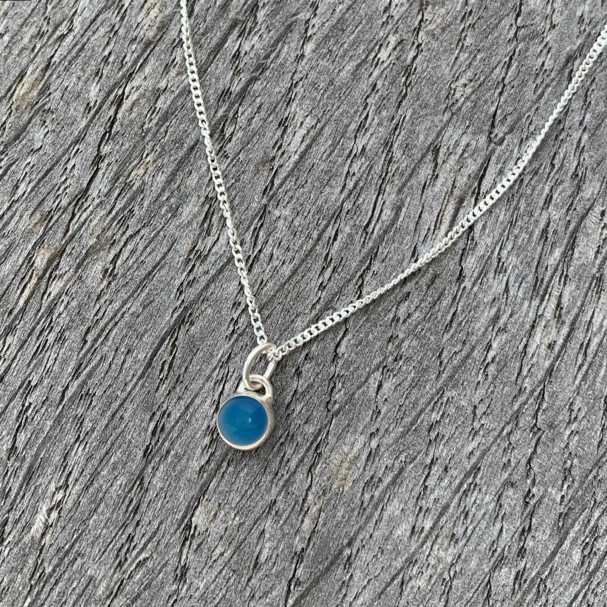 A blue agate stone set in silver on a sterling silver chain.