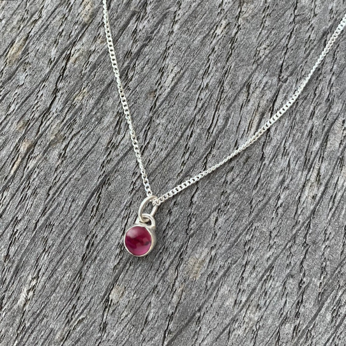 A garnet stone set in silver on a sterling silver chain.