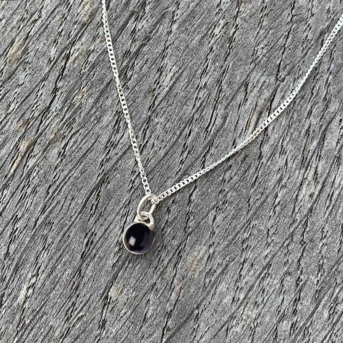 A black onyx stone set in silver on a sterling silver chain.