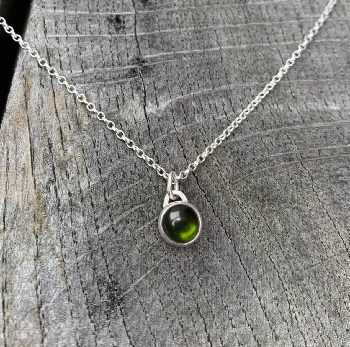 A green tourmaline stone set in silver on a sterling silver chain.