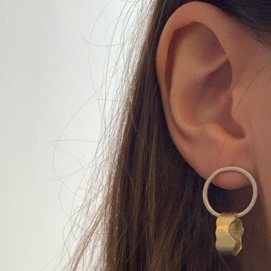 Sterling silver circular stud earrings with oval wavy brass circles attached to form statement earrings, pictured on model.
