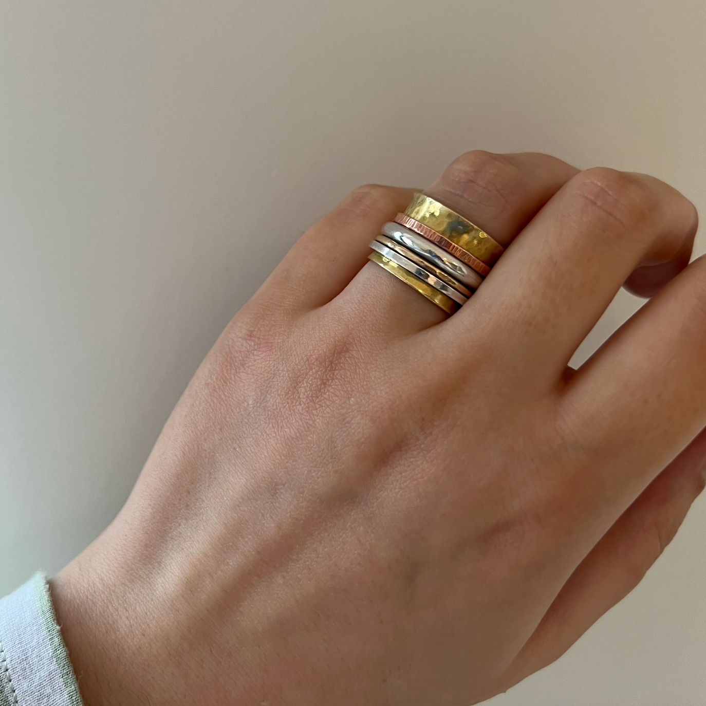 A brass spinner ring with one gold band, one copper band and two silver spinning bands.