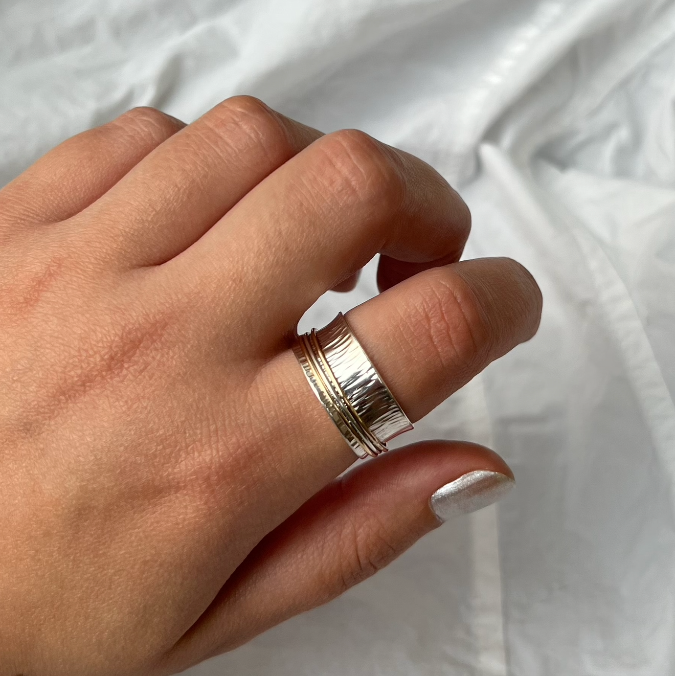 A sterling silver spinner ring with two 9ct gold bands and one silver spinning band.