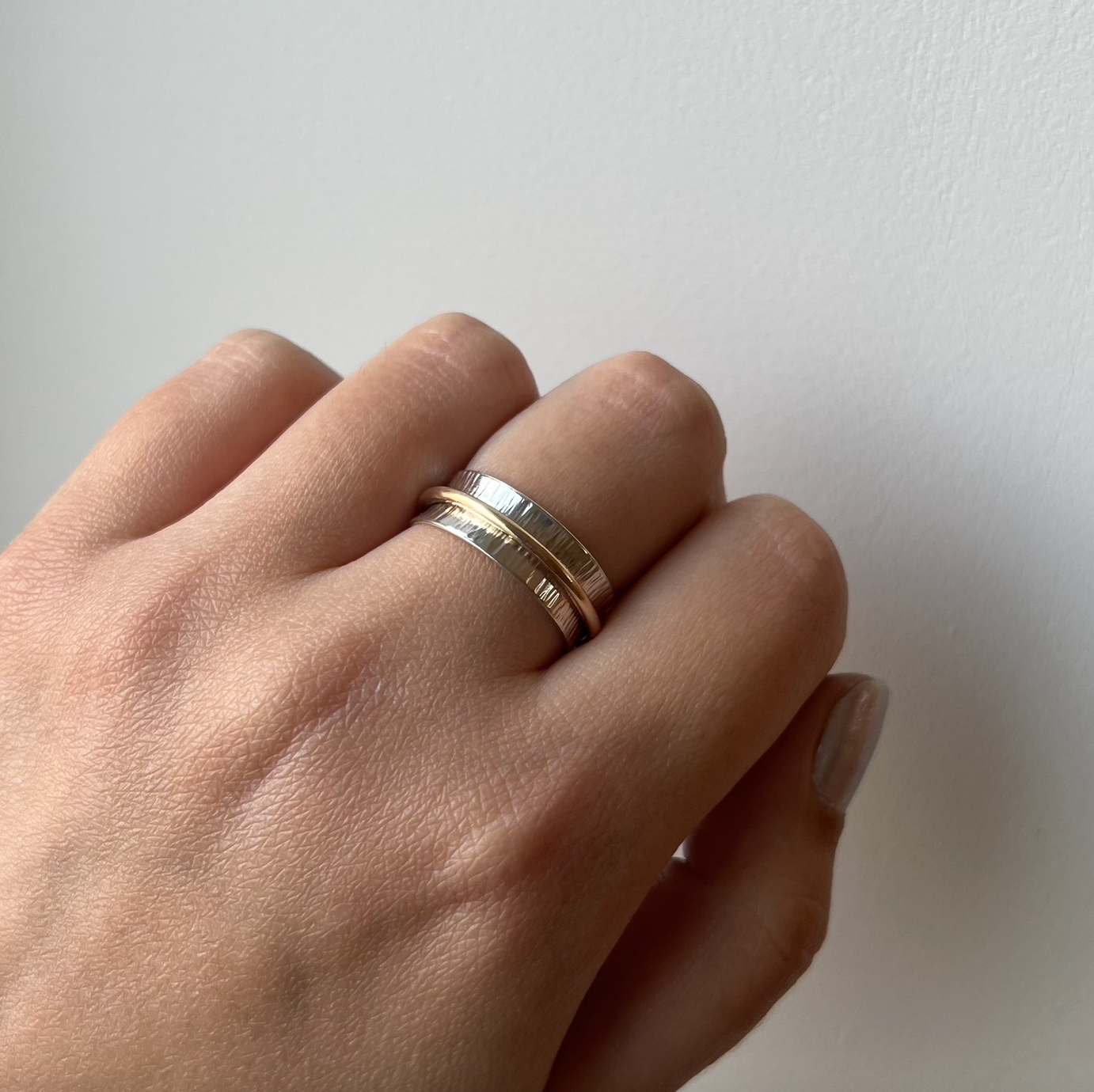 A sterling silver spinner ring with one gold band.