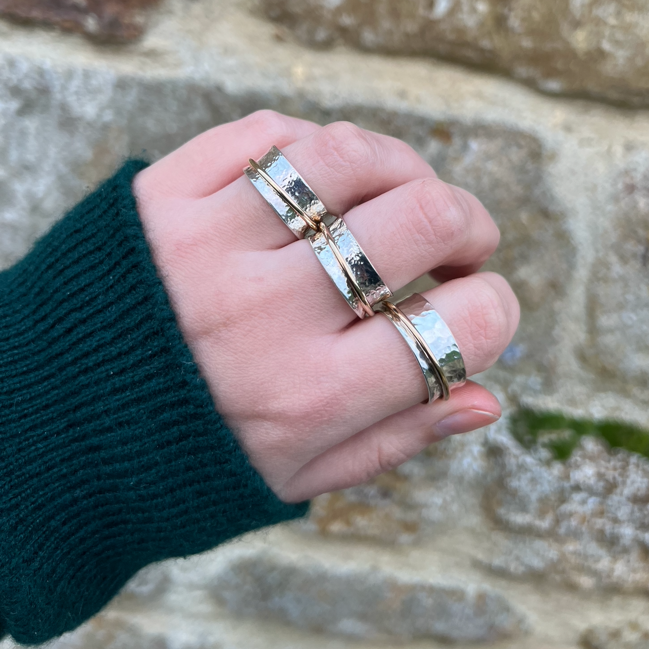 Three sterling silver spinner rings with one gold band.