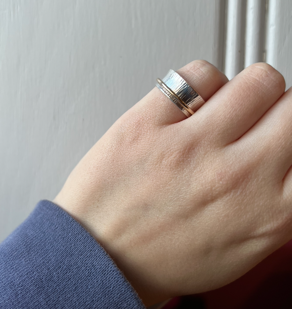 A sterling silver spinner ring with one gold band.