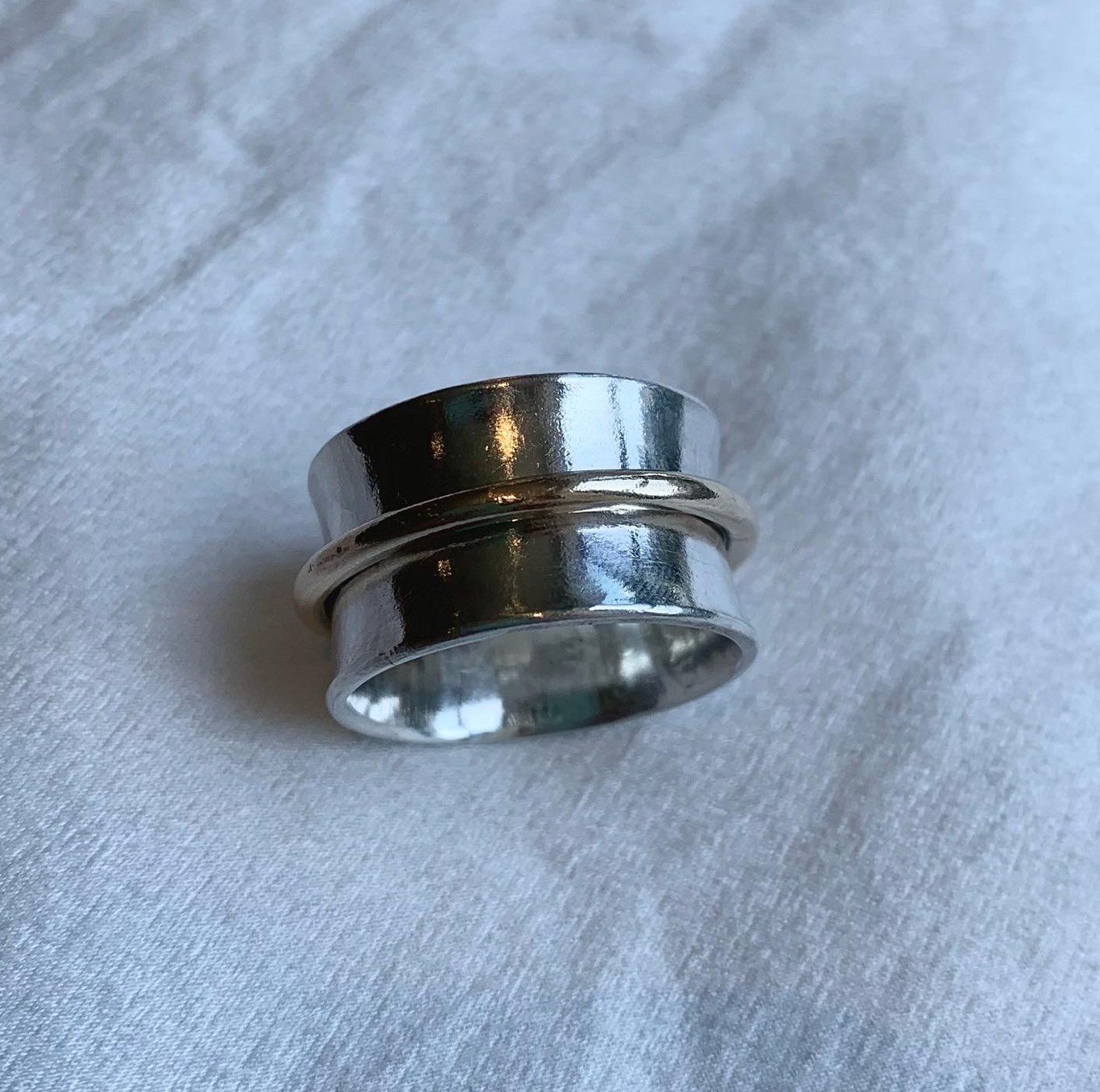 A sterling silver spinner ring with one chunky gold band.