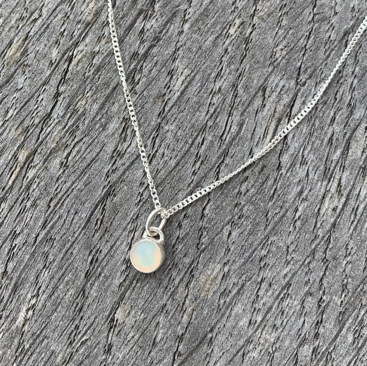 A rainbow opal set charm paired with a sterling silver chain.