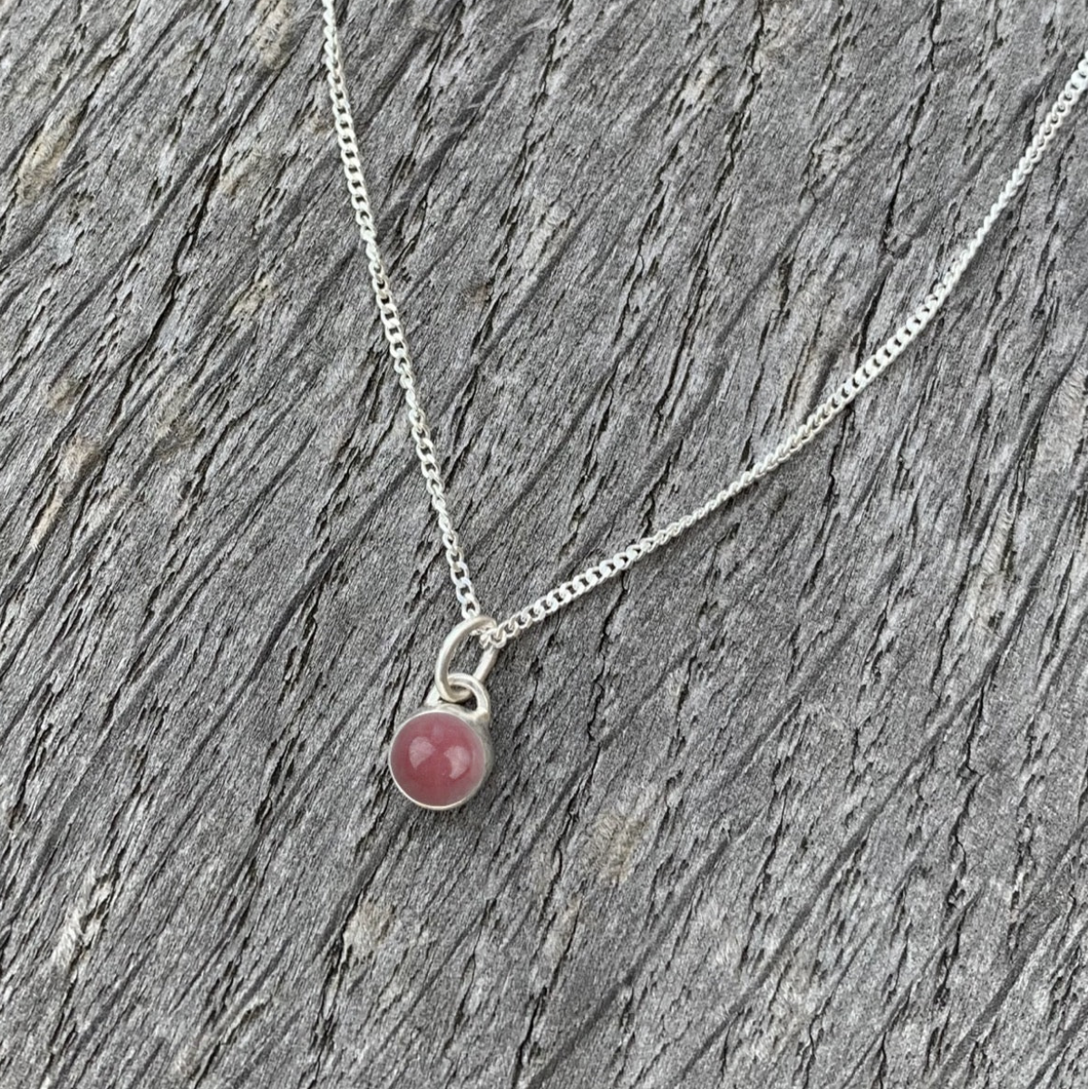 A rhodochrosite and sterling silver charm necklace.