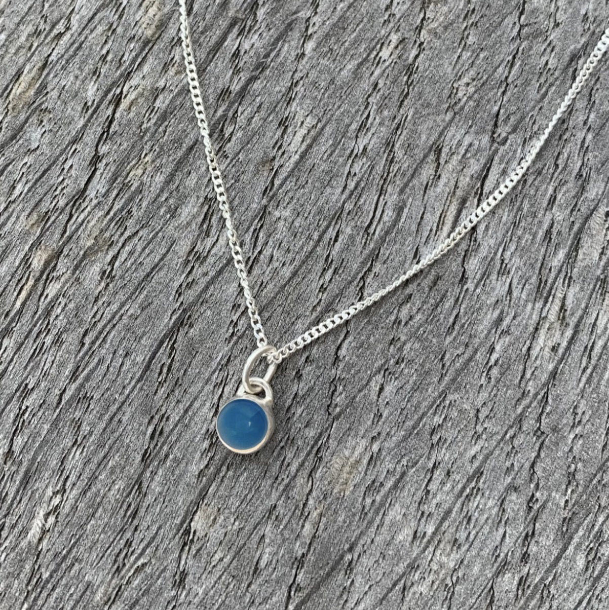 A blue agate and sterling silver charm necklace.