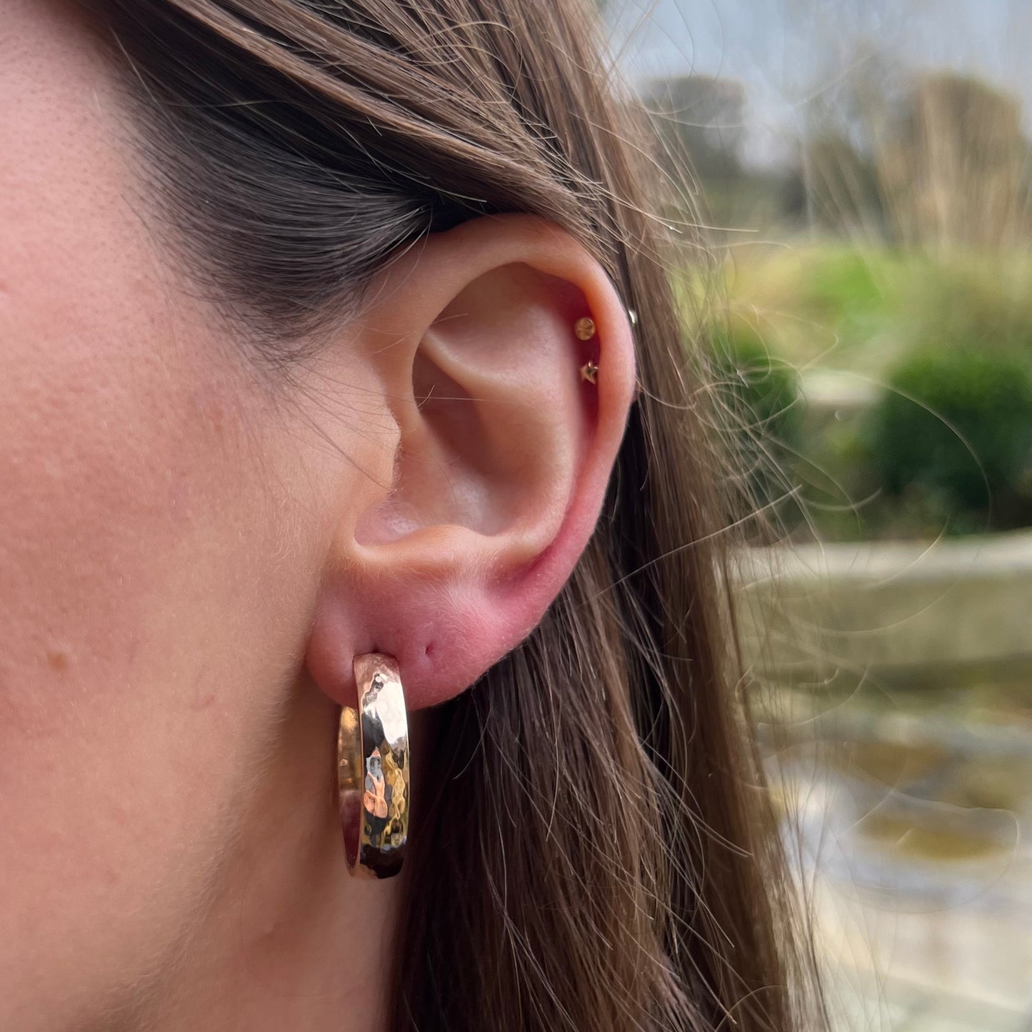 Solid 9ct gold chunky hoop earrings with a hammer texture, pictured on a model.