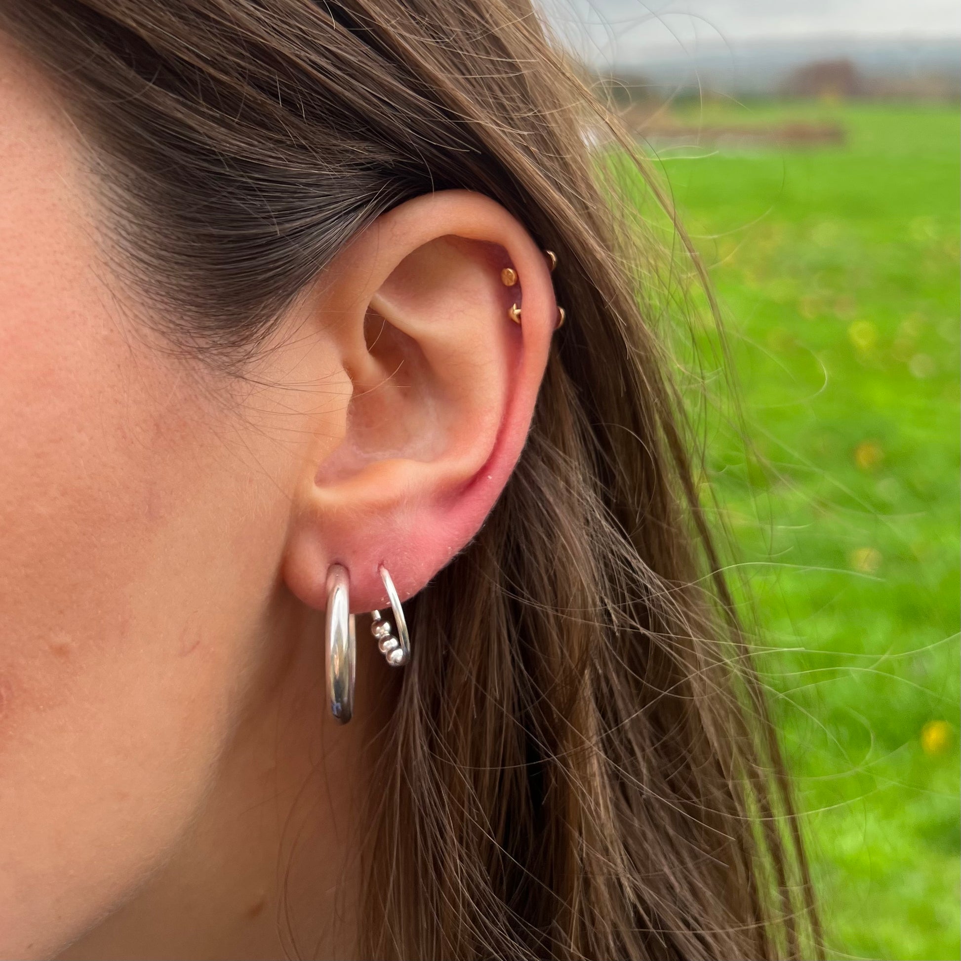 A handmade plain shiny sterling silver hoop earrings , pictured on a model.