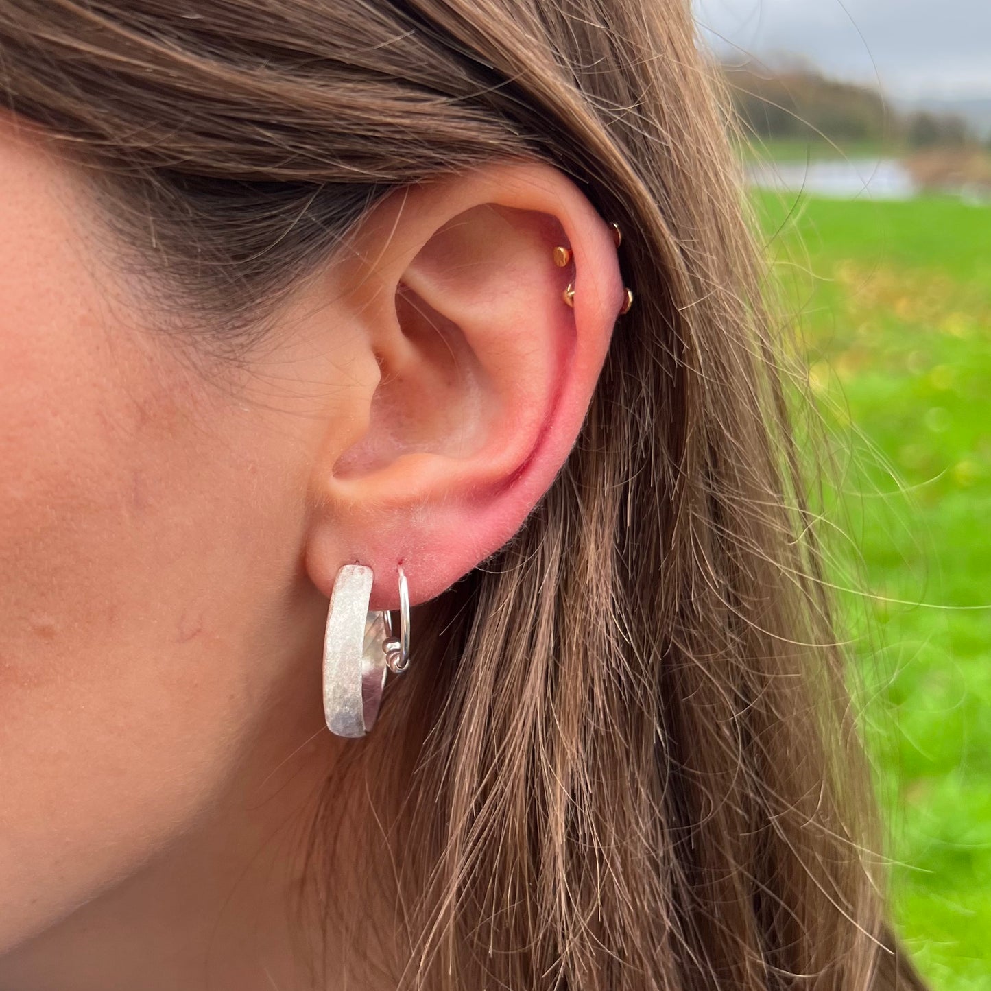 Large sterling silver hoops with a frosted matt texture, pictured on a model.