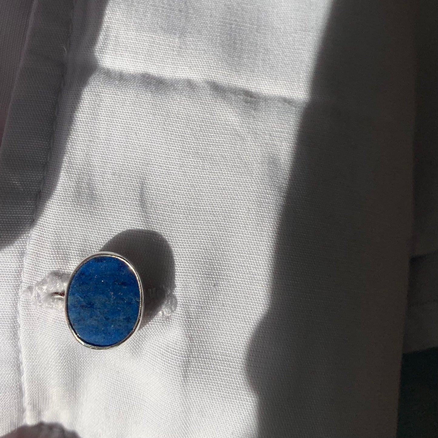 Oval lapis lazuli cufflinks in a white shirt button hole.