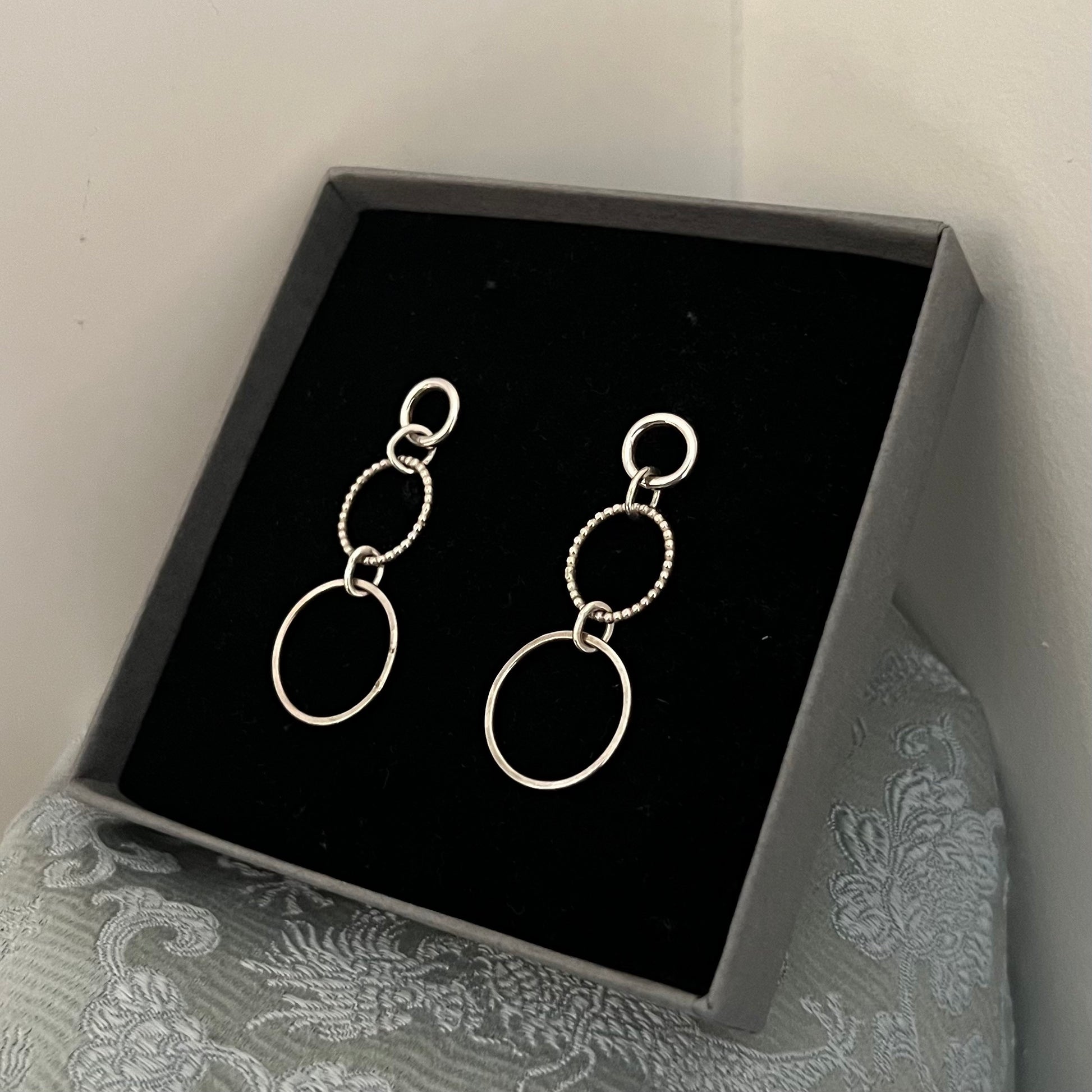 A pair of sterling silver earrings with five silver circles forming a snowman like shape.